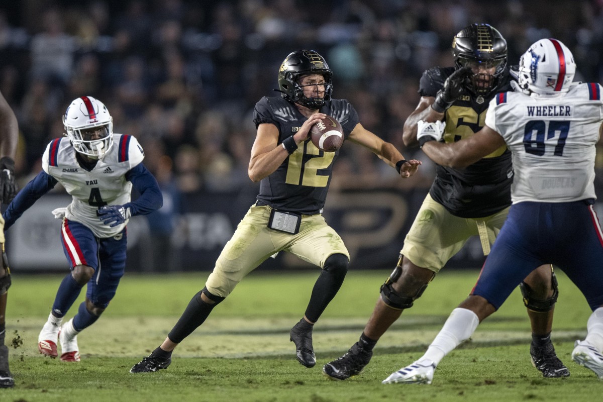 Sep 24, 2022; West Lafayette, Indiana, USA; Purdue Boilermakers quarterback Austin Burton (12) scrambles away from Florida Atlantic Owls safety Teja Young (4) during the second half at Ross-Ade Stadium.